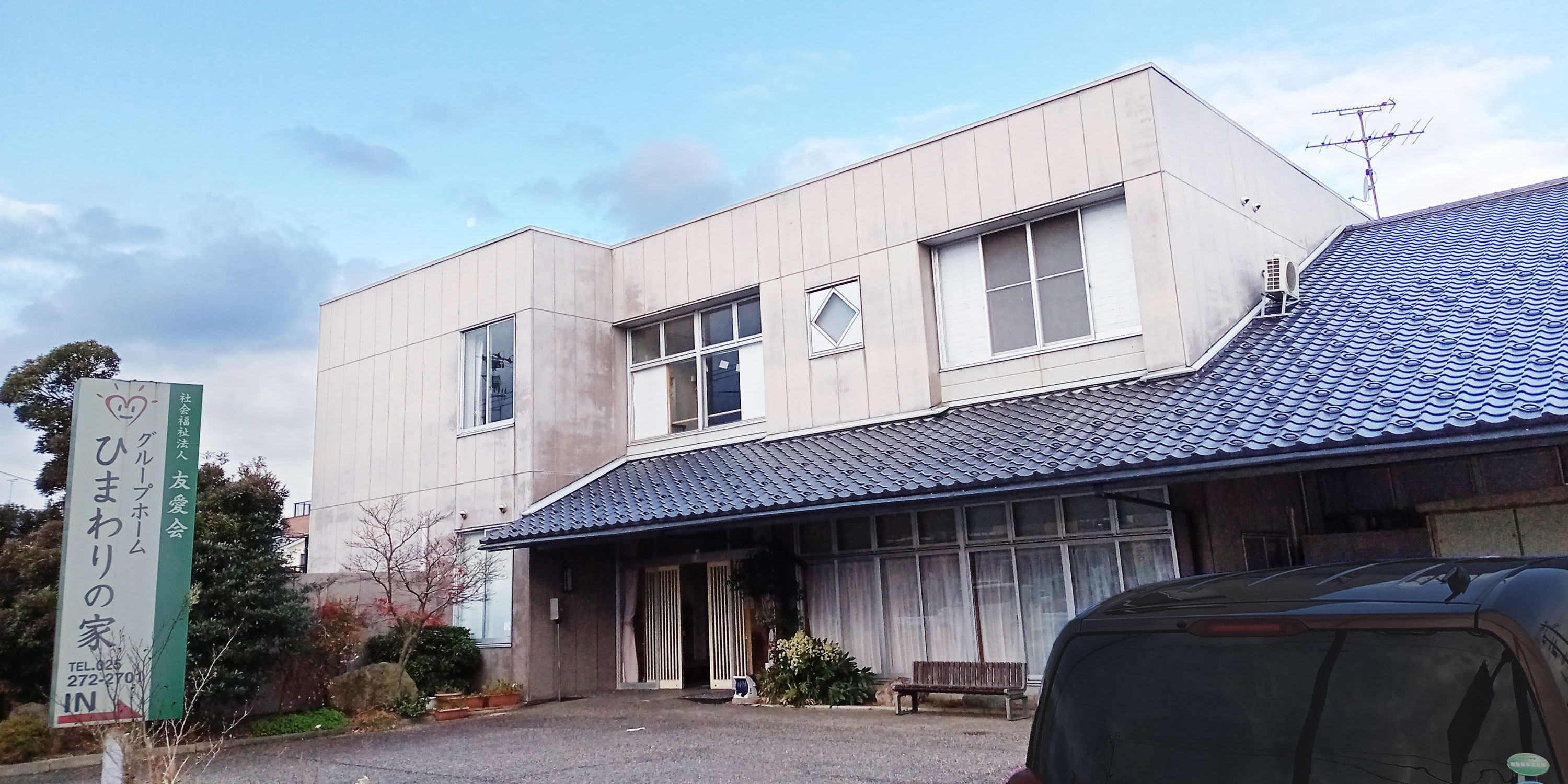 介護施設の建物外観。モダンな白壁造りの2階建て施設。駐車スペース完備。